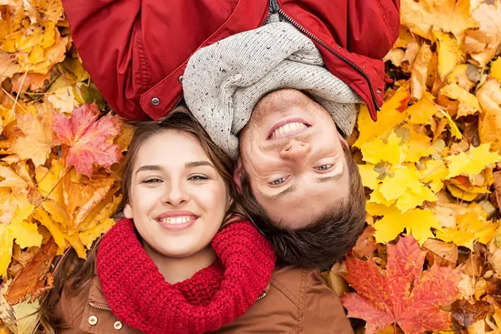 couple laying on a bed of fallen leaves